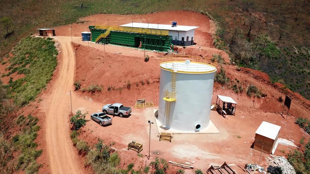 Reservatório apoiado de aço carbono pintado, com escada externa e plataforma superior, instalado em obra industrial em projeto da Faz Forte.