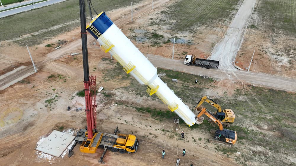 Visão de cima de caixa d'água tipo taça sendo colocada em base para caixa d'água por caminhão e máquinas