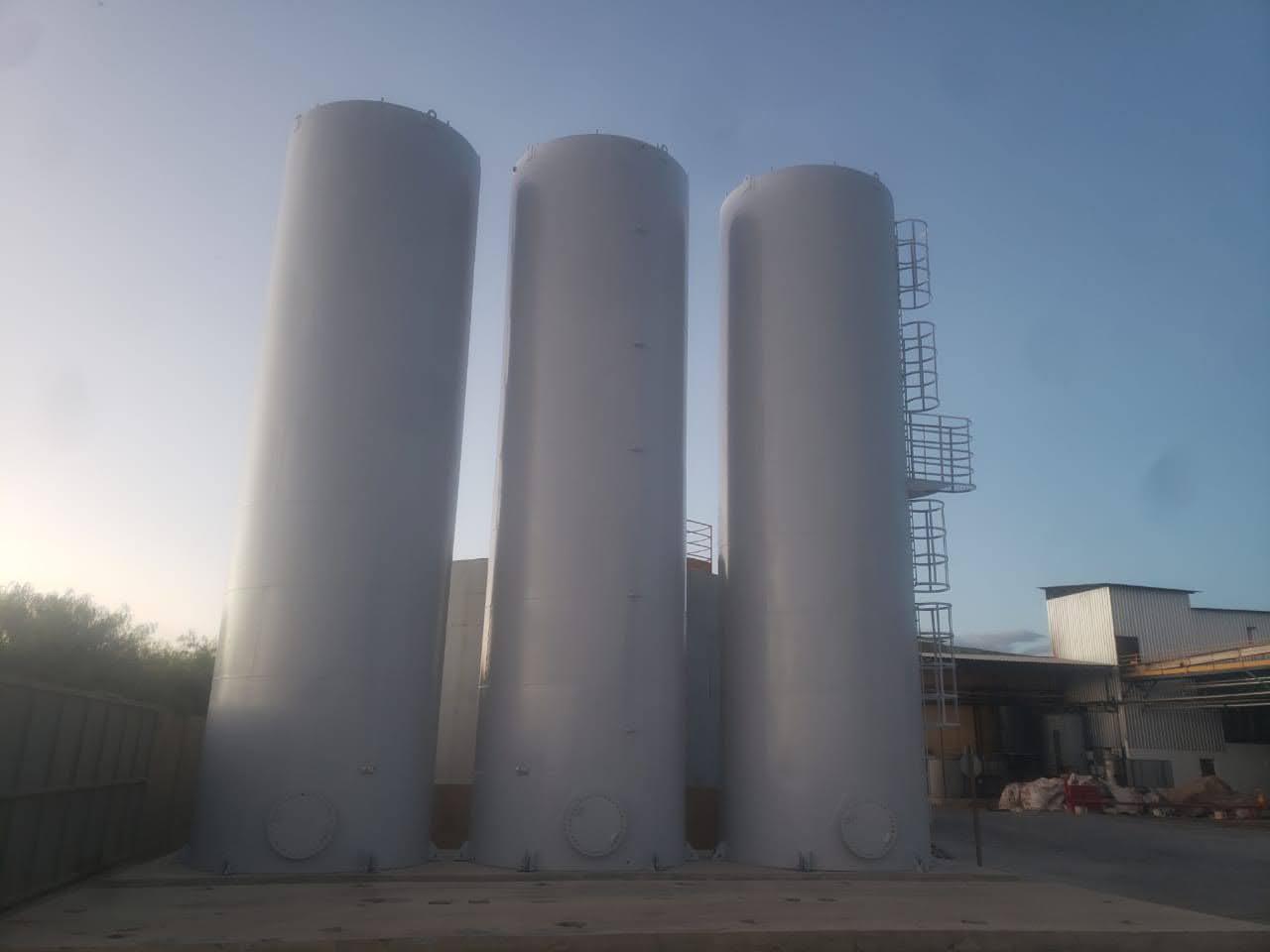 Três caixas d'água cilíndricas brancas uma ao lado da outra