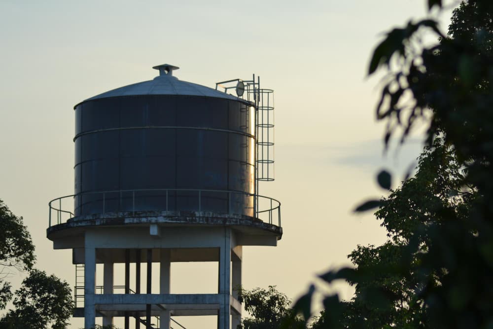 Reservatório de água de grande porte em cima de estrutura com céu ao fundo