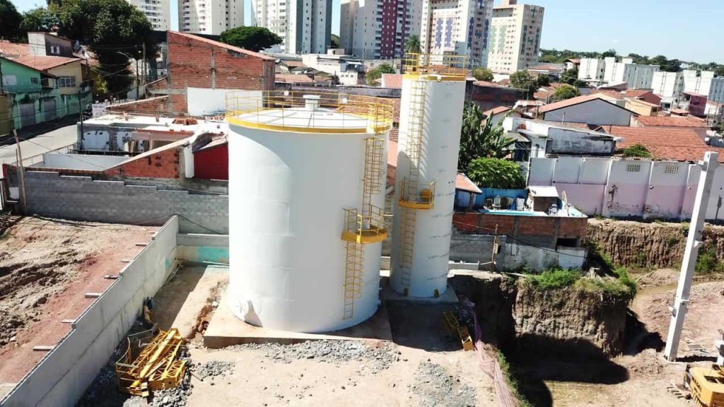 Visão de cima de reservatório de água cercado de casas e prédios em cidade