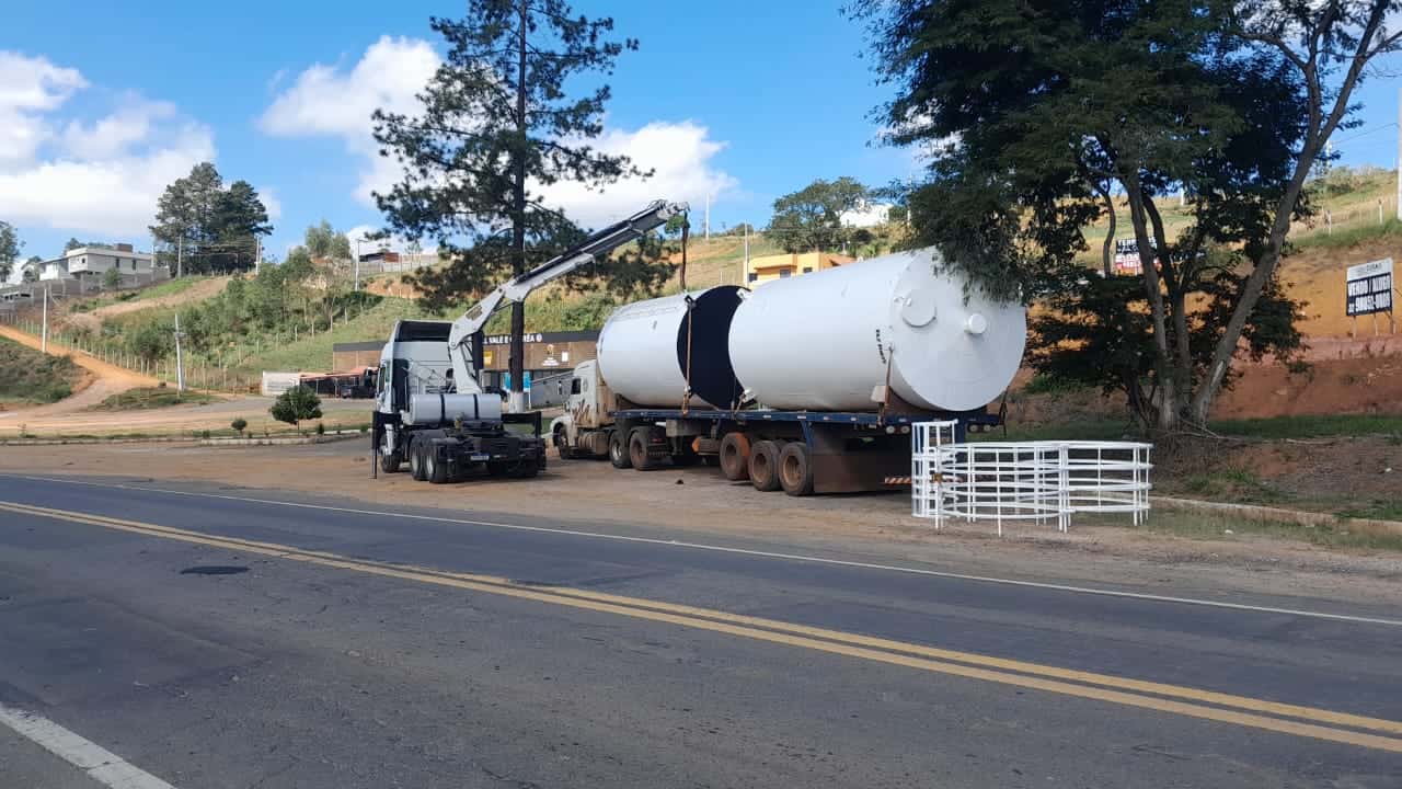 Reservatorio metálico sendo transportado por caminhão em área litorânea